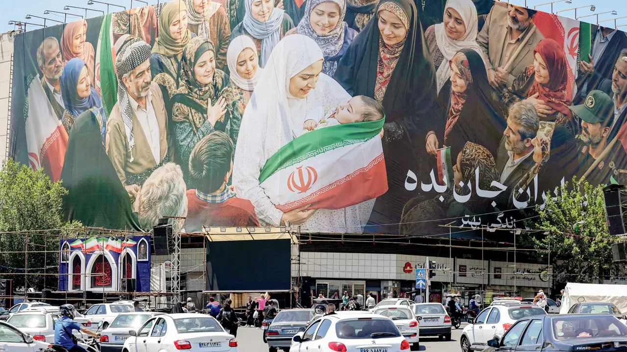 Motorists drive past a large political billboard along Enghelab Square in central Tehran on Tuesday. PIC/AFP