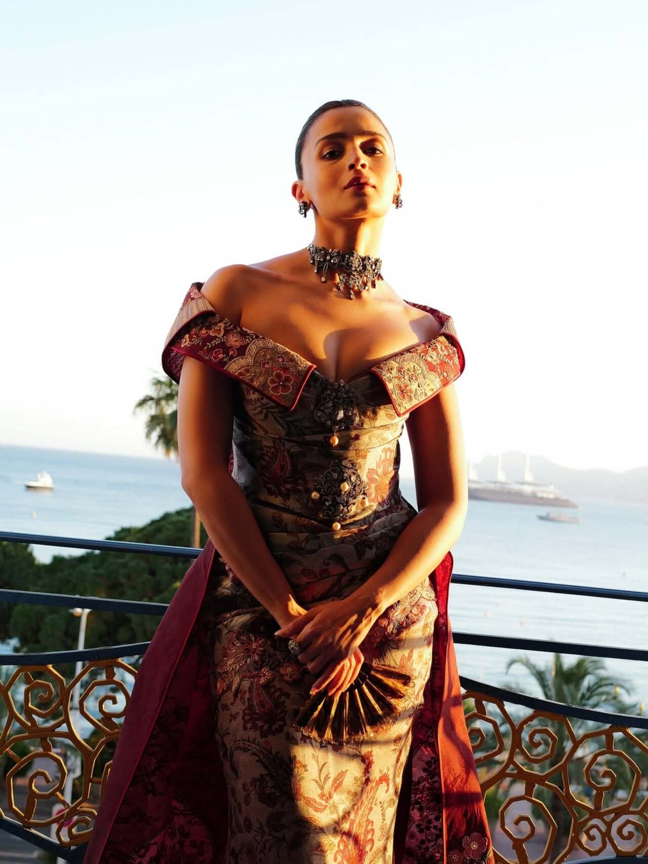 The red gown featured intricate hand-painted floral embroidery in deep burgundy and muted ivory shades, inspired by historical chintz textile artistry The red gown featured intricate hand-painted floral embroidery in deep burgundy and muted ivory shades, inspired by historical chintz textile artistry