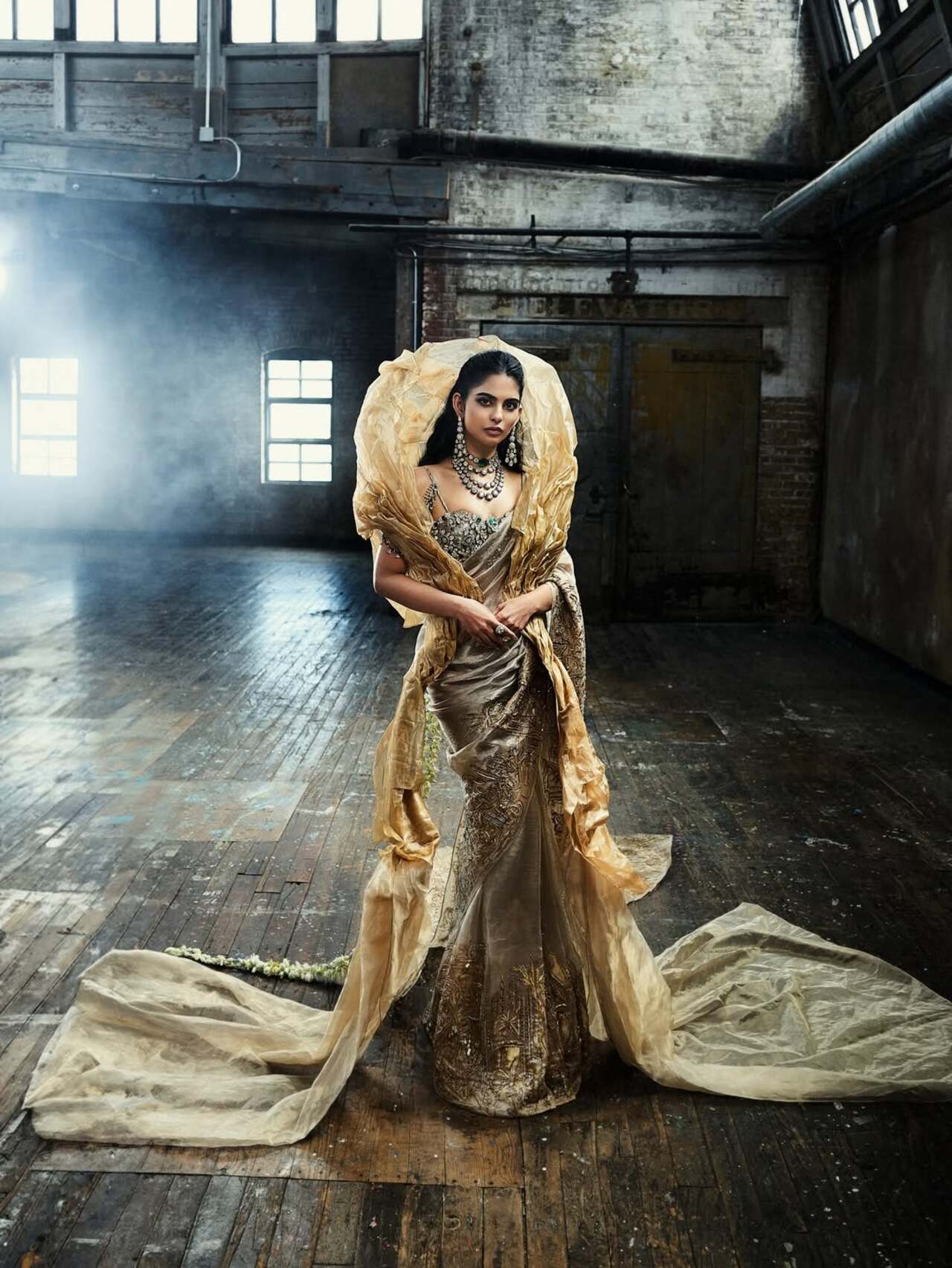 Isha Ambani wore a custom couture saree by Gaurav Gupta, created in collaboration with Swadesh artisans. The saree was woven with threads of pure gold and featured hand-painted pichwai-inspired motifs in soft gold and earthy tones. The design presented the saree as an artistic form, with a sculptural drape. The entire outfit was crafted over 1200 hours by over 50 artisans.