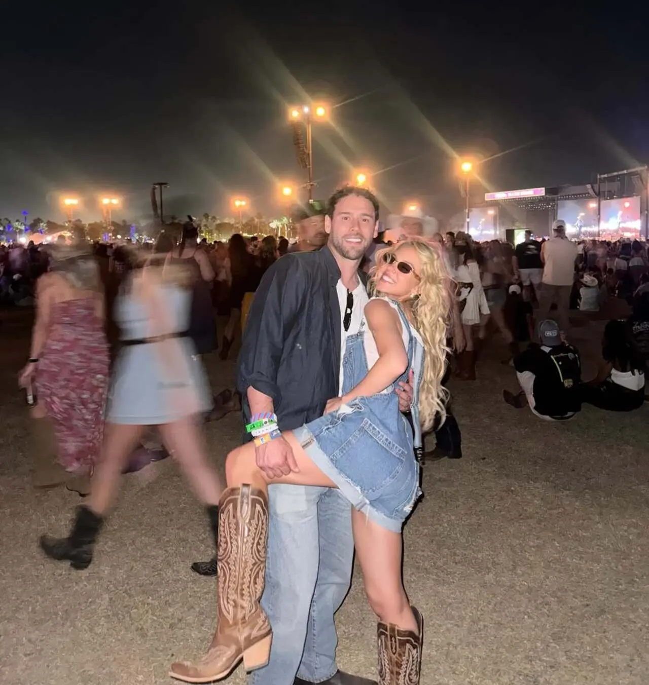 For the concert, Sydney stuns in classic brown cowboy boots and denim overalls, while Scooter smiles warmly beside her in a casual dark shirt and jeans.