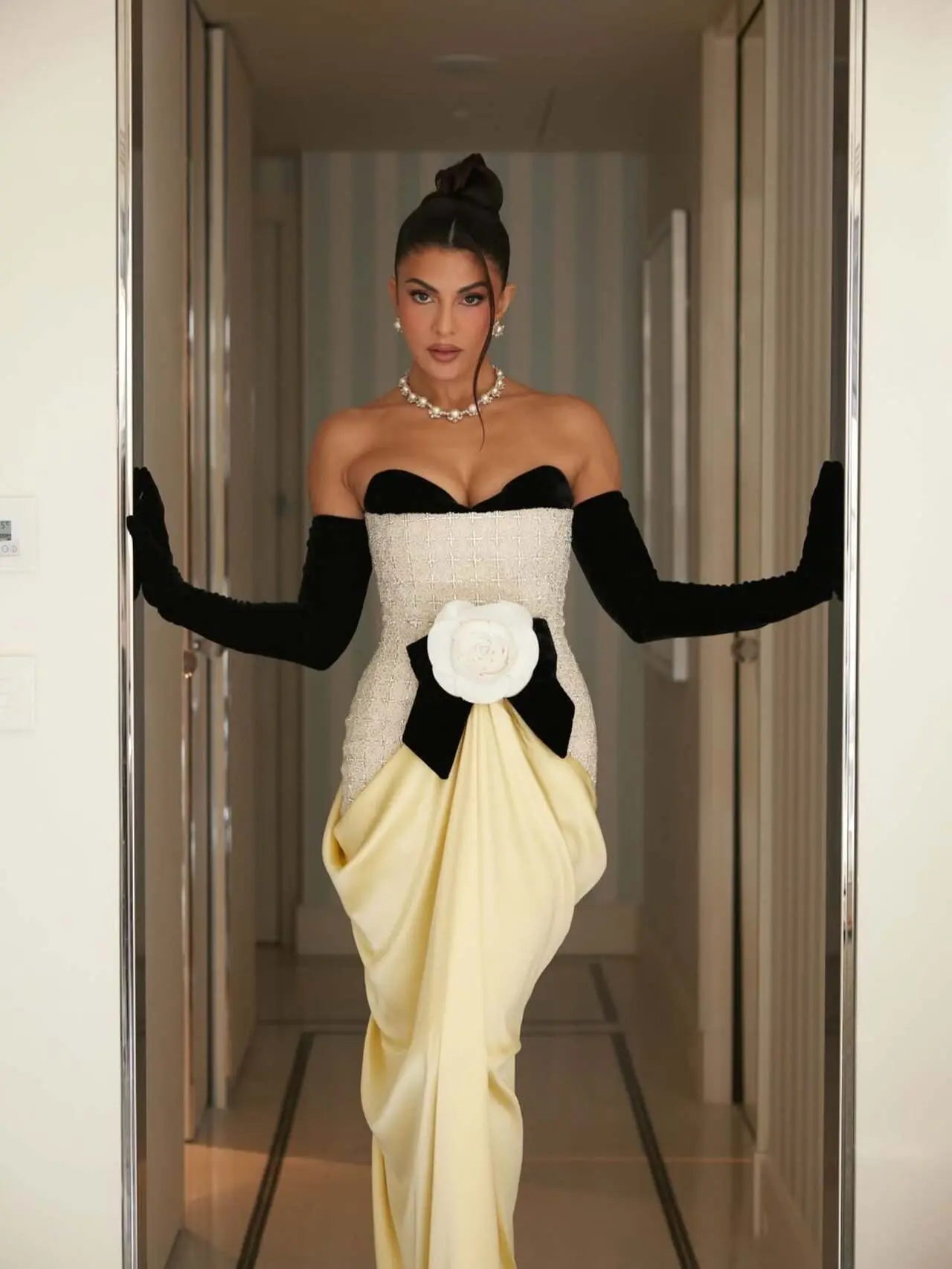 The structured strapless gown featured a dramatic silhouette in ivory tones paired with statement black opera gloves, creating a timeless yet fashion forward aesthetic.