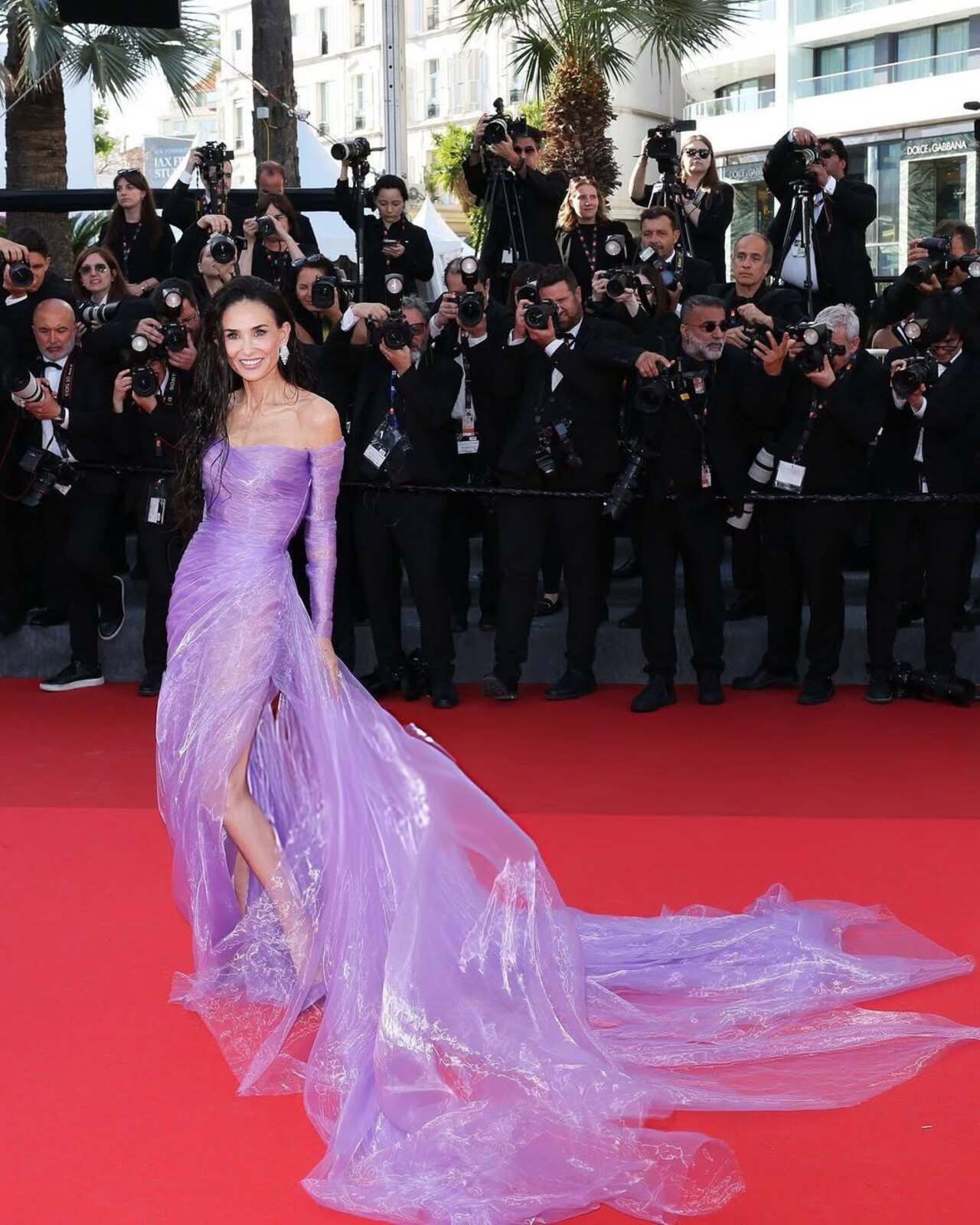 At Cannes 2026, jury member Demi Moore captivated the red carpet in an ethereal, custom iridescent lilac silk organza gown by Gucci. Styled by Brad Goreski, the fluid design featured a sweetheart neckline, a ruched strapless bodice, and sheer long sleeves. A daring thigh-high slit and a sweeping, wind-blown train injected dramatic movement. She paired the look with matching purple satin pumps, statement Chopard diamond chandelier earrings, and a striking, waist-length wet-look hairstyle. At Cannes 2026, jury member Demi Moore captivated the red carpet in an ethereal, custom iridescent lilac silk organza gown by Gucci. Styled by Brad Goreski, the fluid design featured a sweetheart neckline, a ruched strapless bodice, and sheer long sleeves. A daring thigh-high slit and a sweeping, wind-blown train injected dramatic movement. She paired the look with matching purple satin pumps, statement Chopard diamond chandelier earrings, and a striking, waist-length wet-look hairstyle.