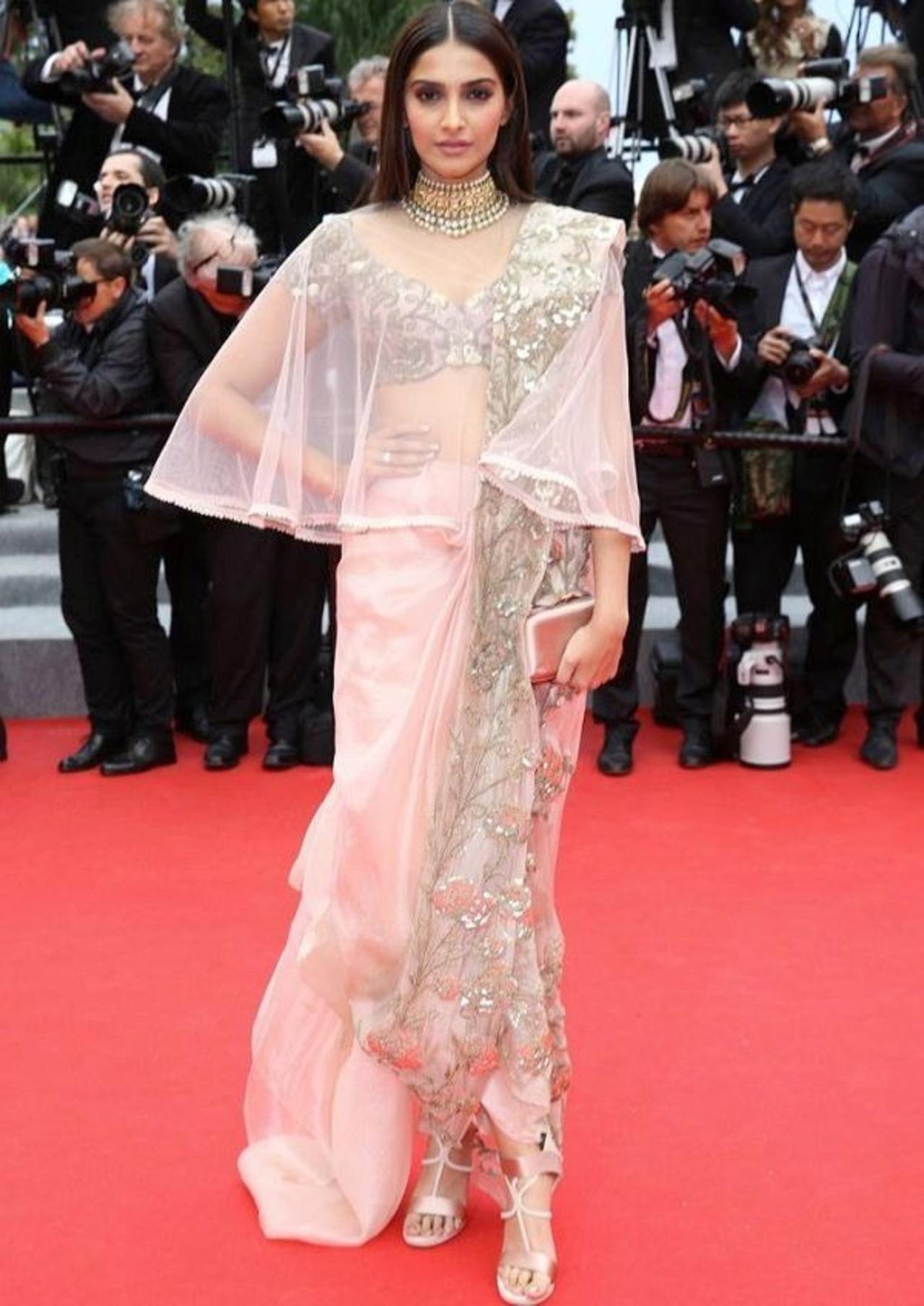 Sonam Kapoor wore a fusion sari-gown designed by Indian designer Anamika Khanna.The pale pink, draped sari was paired with an intricately embroidered blouse and a sheer cape as she arrived at 2014 Cannes Film Festival.