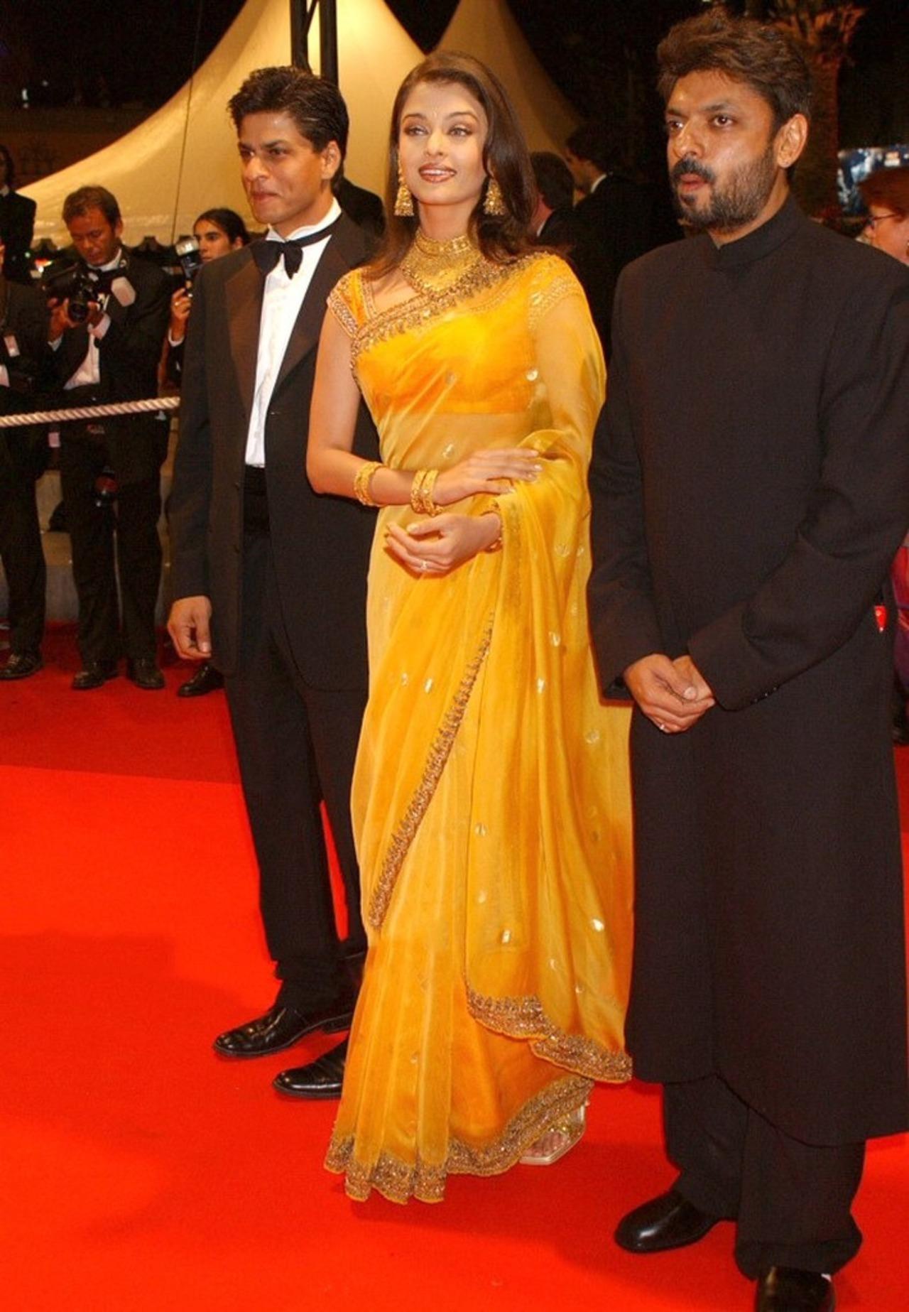 Aishwarya Rai debuted at the 2002 Cannes Film Festival alongside actor Shah Rukh Khan and director Sanjay Leela Bhansali. She wore a traditional yellow saree designed by Neeta Lulla for her debut.