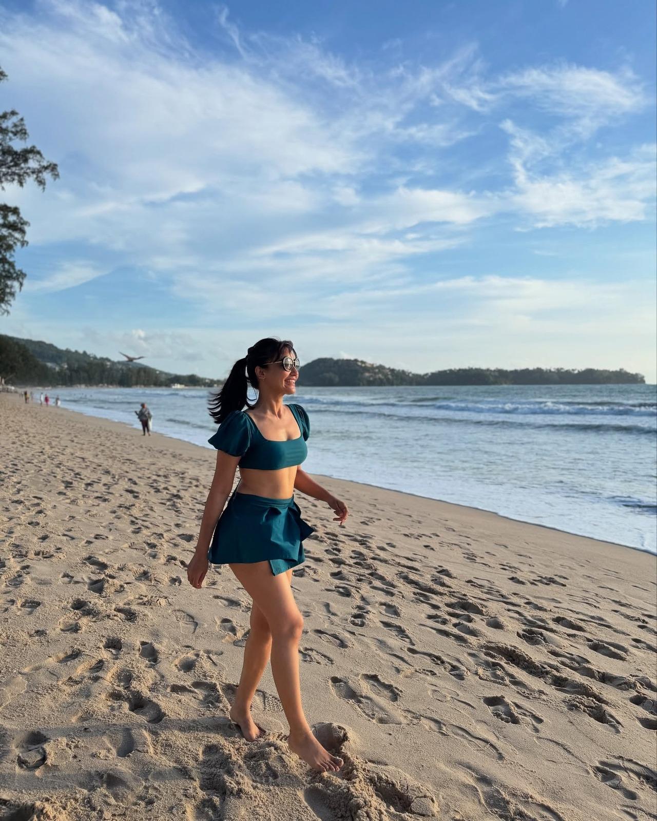 Bringing out her young, energetic and bubbly side, Surbhi wears this teal square-neck crop top with puff sleeves and a back tie-up, paired with a matching high-waisted skirt that includes a pleated design for a fun day at the beach. Bringing out her young, energetic and bubbly side, Surbhi wears this teal square-neck crop top with puff sleeves and a back tie-up, paired with a matching high-waisted skirt that includes a pleated design for a fun day at the beach.