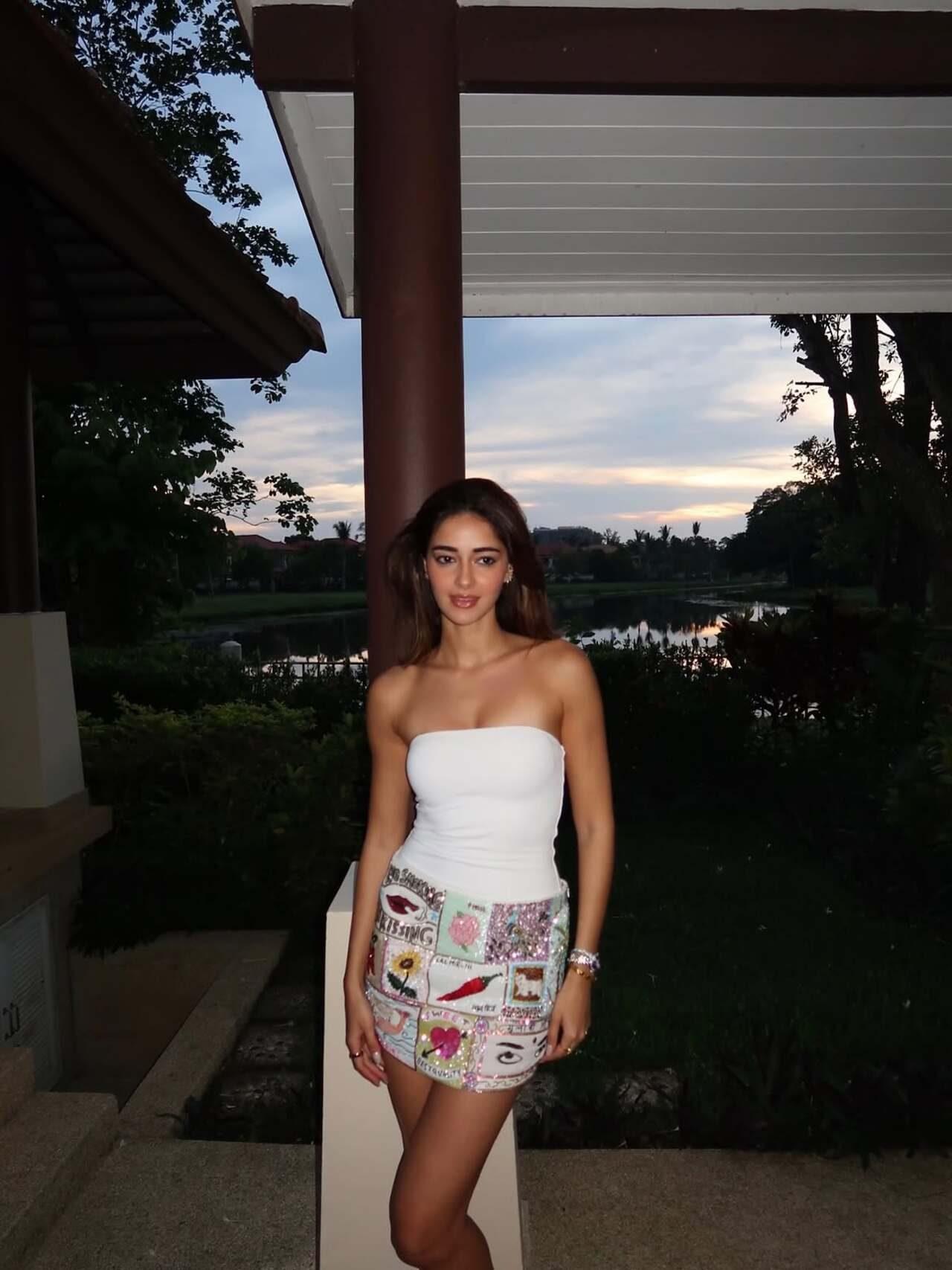 Ananya Panday poses during golden hour in a white strapless tube top and embellished patchwork mini skirt, with a serene lake and tropical greenery creating a dreamy backdrop Ananya Panday poses during golden hour in a white strapless tube top and embellished patchwork mini skirt, with a serene lake and tropical greenery creating a dreamy backdrop