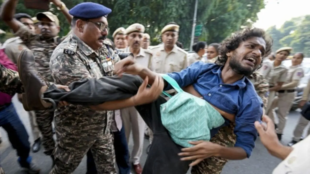 Anti-SIR protest: Delhi Police detain demonstrators marching towards EC Security personnel detain an activist during a Delhi protest demanding CEC Gyanesh Kumar’s resignation over electoral roll revision. Pic/ PTI