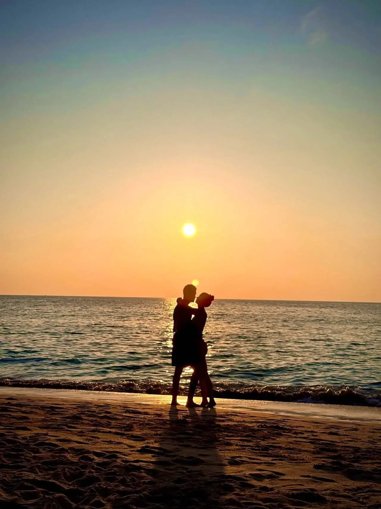 Hrithik Roshan and Saba Azad share a romantic kiss by the sea, silhouetted against a stunning sunset