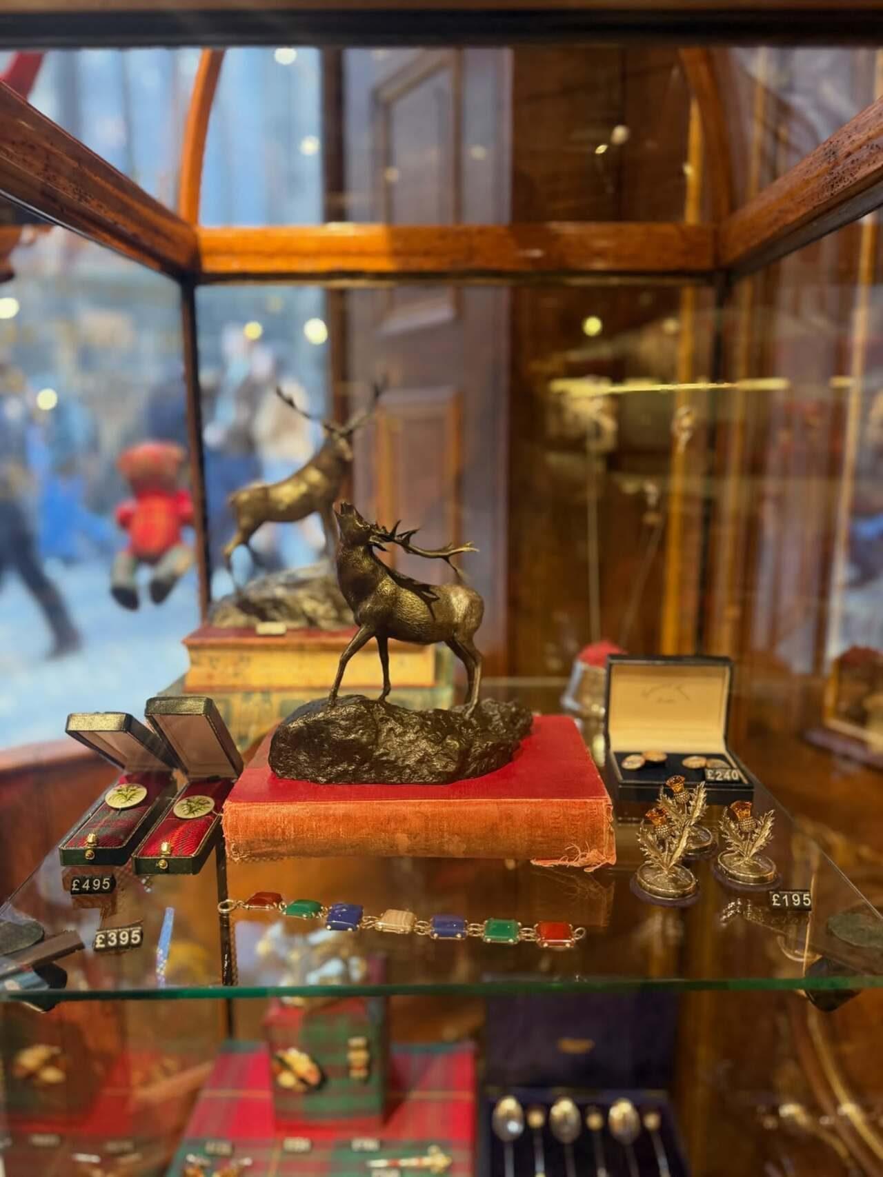 A bronze stag figurine, silver thistle ornaments and gem-studded bracelets fill a polished display case, offering a glimpse of Scotland-inspired keepsakes