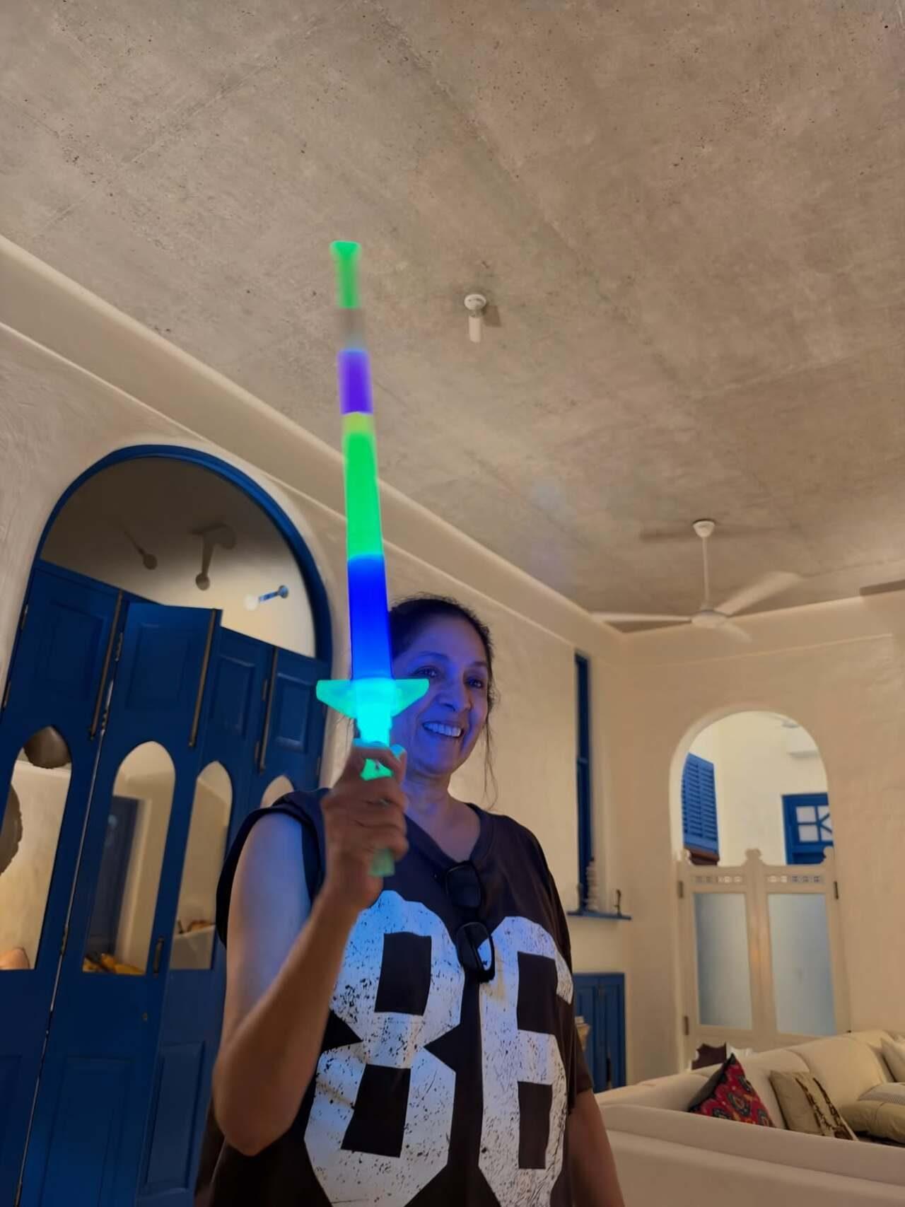 Neena Gupta poses with a glowing, multicoloured toy lightsaber in a cheerful indoor moment, with the getaway’s distinctive blue doors in the background Neena Gupta poses with a glowing, multicoloured toy lightsaber in a cheerful indoor moment, with the getaway’s distinctive blue doors in the background