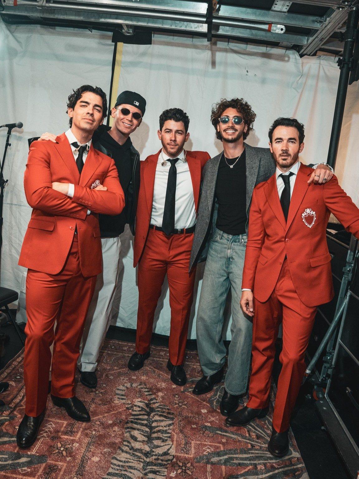 Nick Jonas posed with his brothers and bandmates in matching red tuxedo sets. The group looked stage-ready as they came together for a picture during their tour. Nick Jonas posed with his brothers and bandmates in matching red tuxedo sets. The group looked stage-ready as they came together for a picture during their tour.