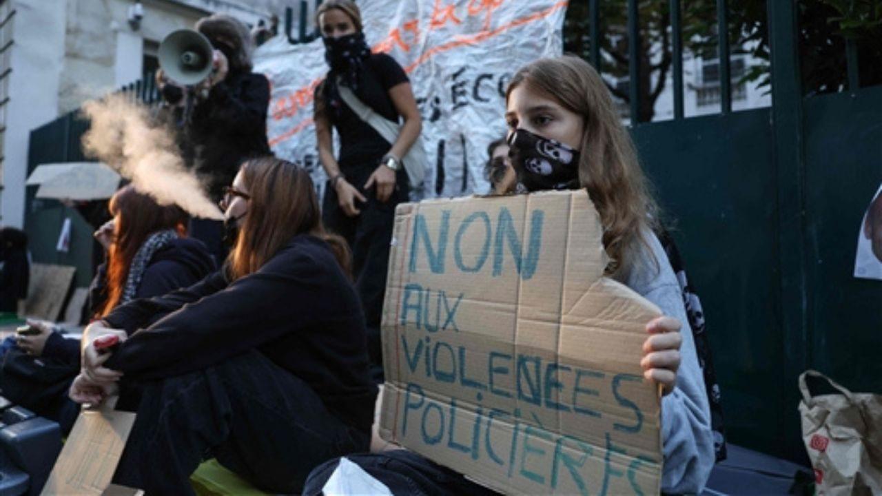 A protester holds a placard reading "No to police violence" as students carry out a blocking protest at the Simone Veil secondary school