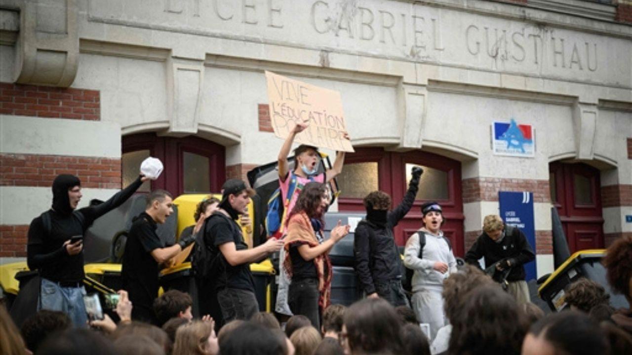 Students stand on bins piled at the entrance as they carry out a blocking protest at the Gabriel Guist'hau secondary school