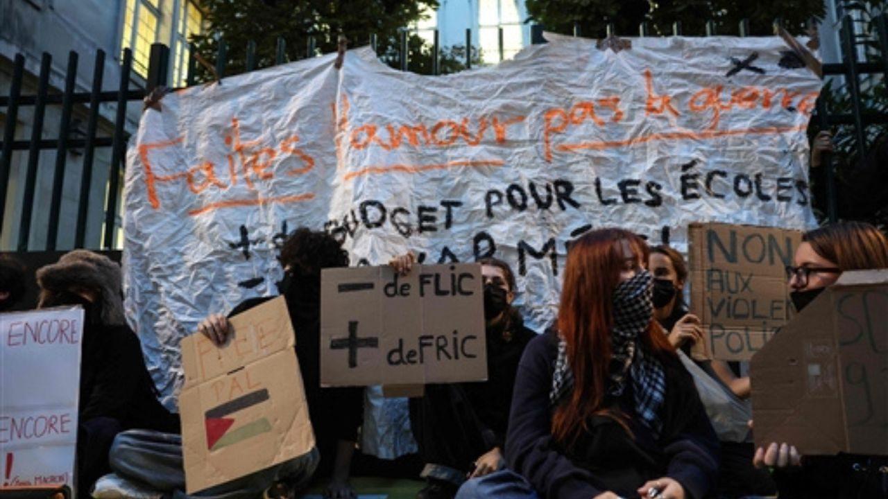 Students sit with a banner reading "Make love not war" as they carry out a blocking protest at the Simone Veil secondary school during a day of nationwide public sector strikes and demonstrations, in Paris