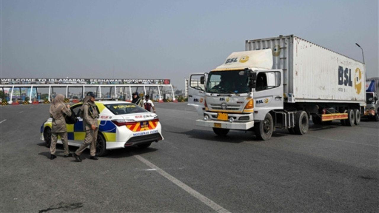 Police personnel stand near the Islamabad–Peshawar Motorway blocked with trucks placed by authorities. Pic/AFP