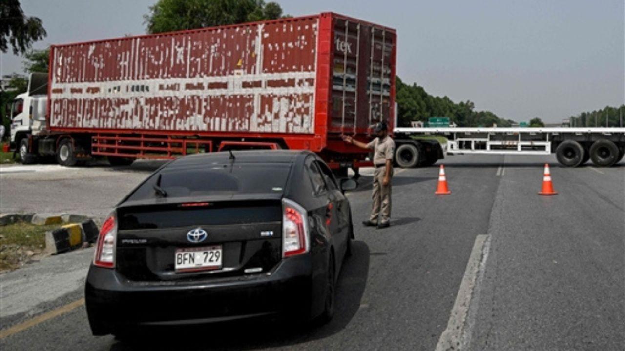 A police officer diverts traffic on the Islamabad–Peshawar Motorway blocked with trucks placed by authorities in Islamabad. Pic/AFP