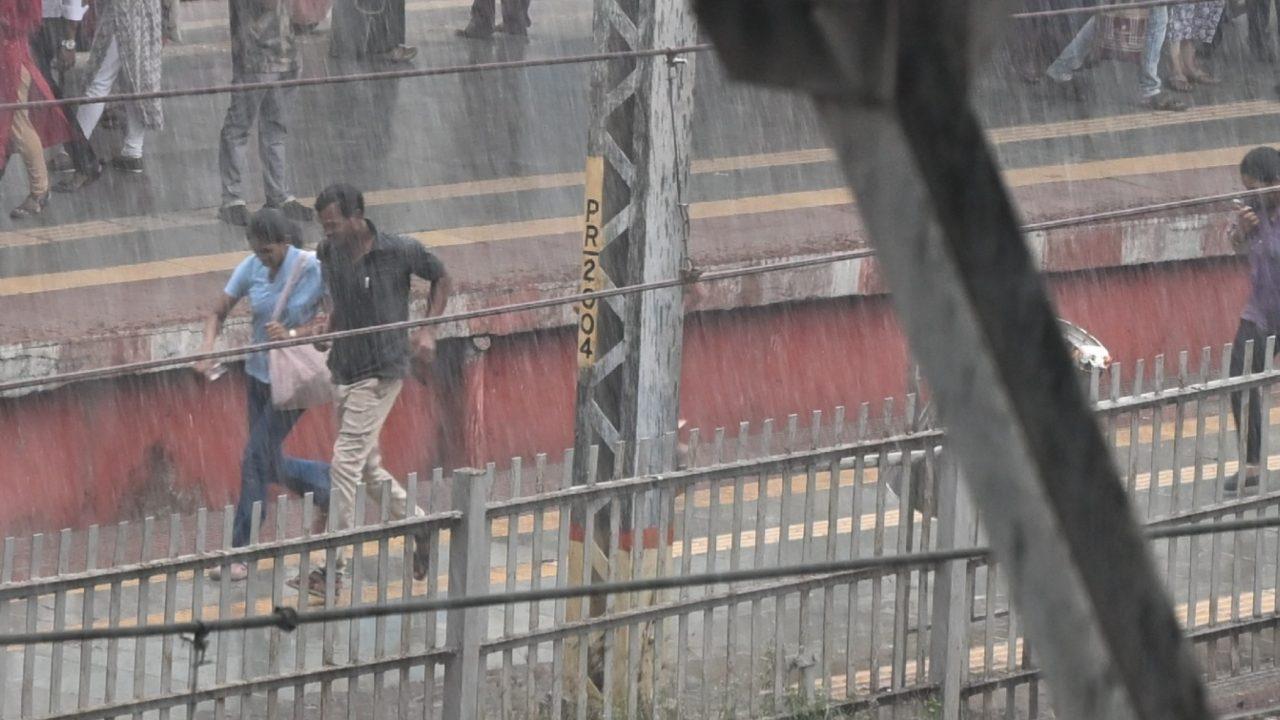 Commuters at a railway station were seen rushing for cover as heavy rain hit parts of the city