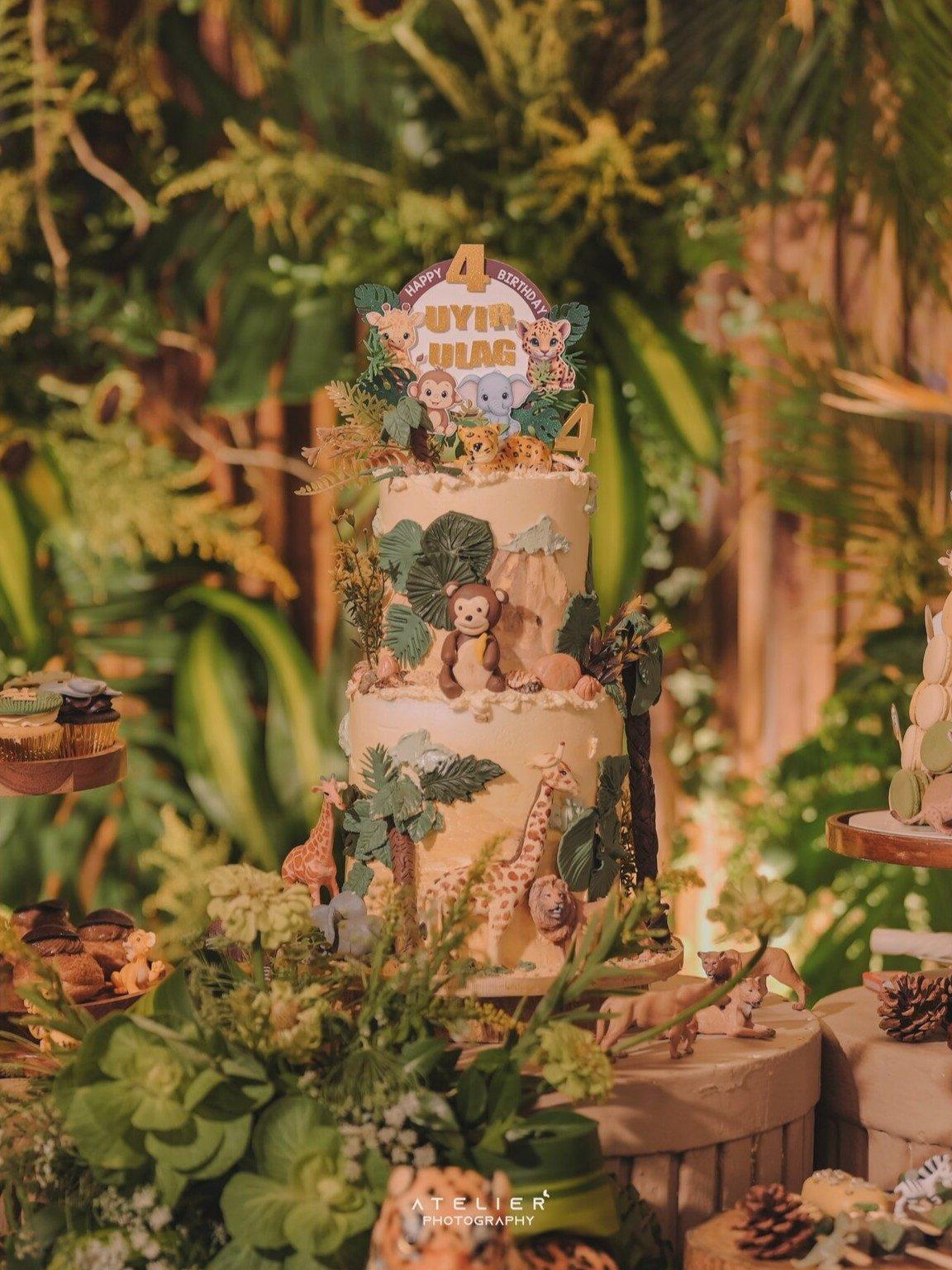 A neon sign reading “Happy Birthday Uyir &amp; Ulag” lit up the rustic setting, while the dessert table featured a two-tiered safari cake, themed macarons and animal-shaped cupcakes.