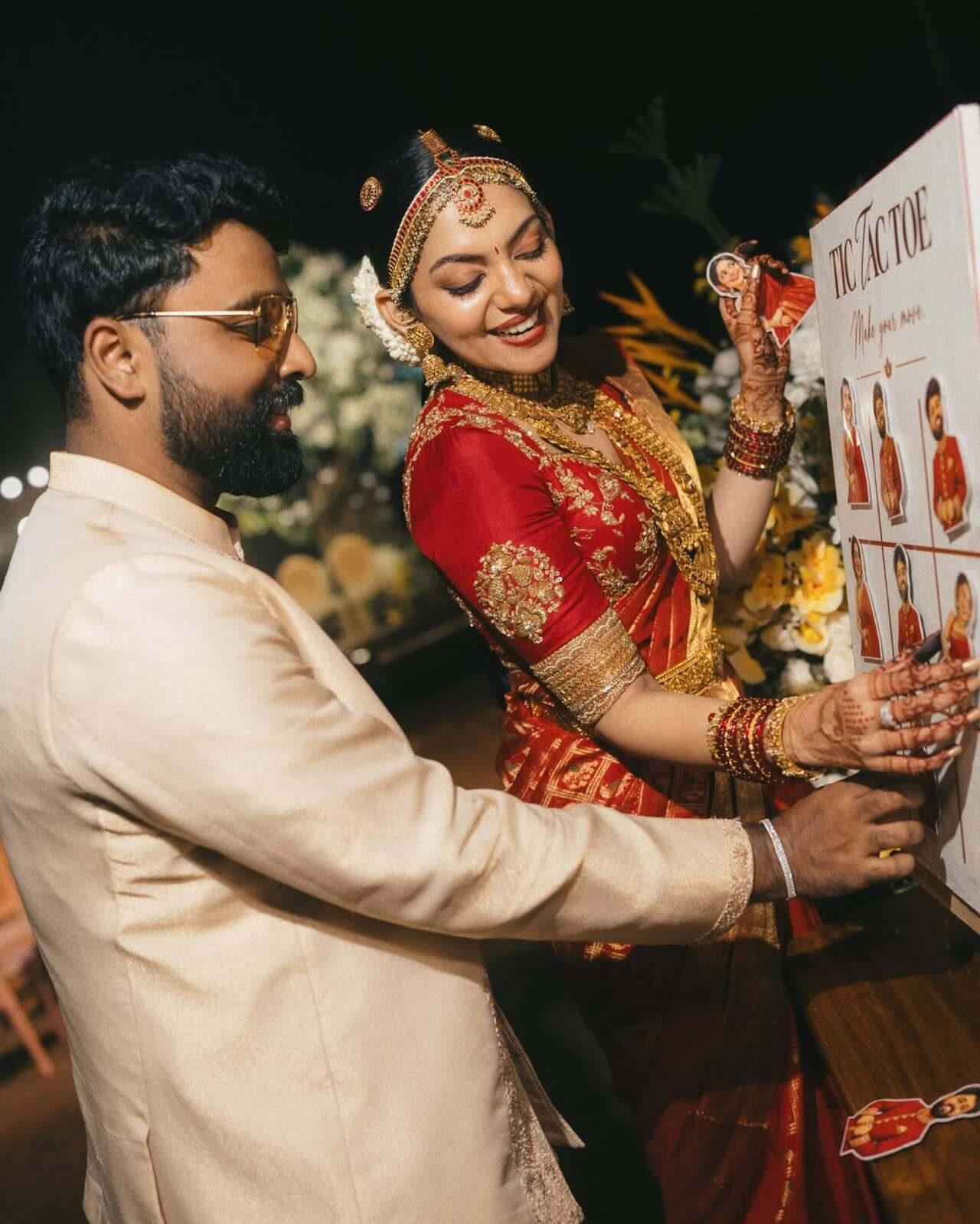 Wedding with no games is no fun, the candid click shows the couple engaging in a playful tic-tac-toe game set up on a customized white display board. Instead of traditional marks, the board features cutout photos of themselves. Ahaana holds up her photo card with a bright smile while Nimish carefully places his piece onto the board, adding a fun, personalized touch to the occasion