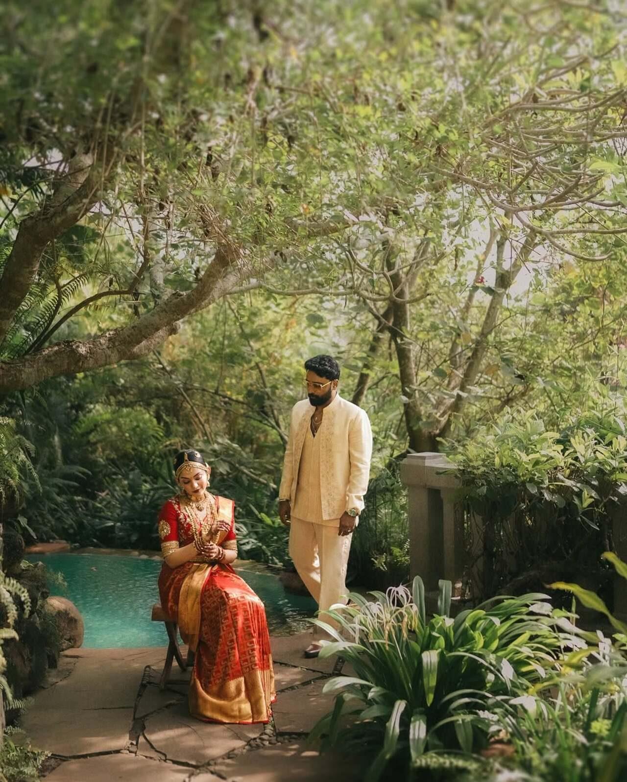 Ahaana sits gracefully on a wooden stool along a stone pathway. As she adjusts her bangles, Nimish walks towards her, making the frame look like a divine painting. The moment is pure cinema as it gives a glimpse into their decade long romance