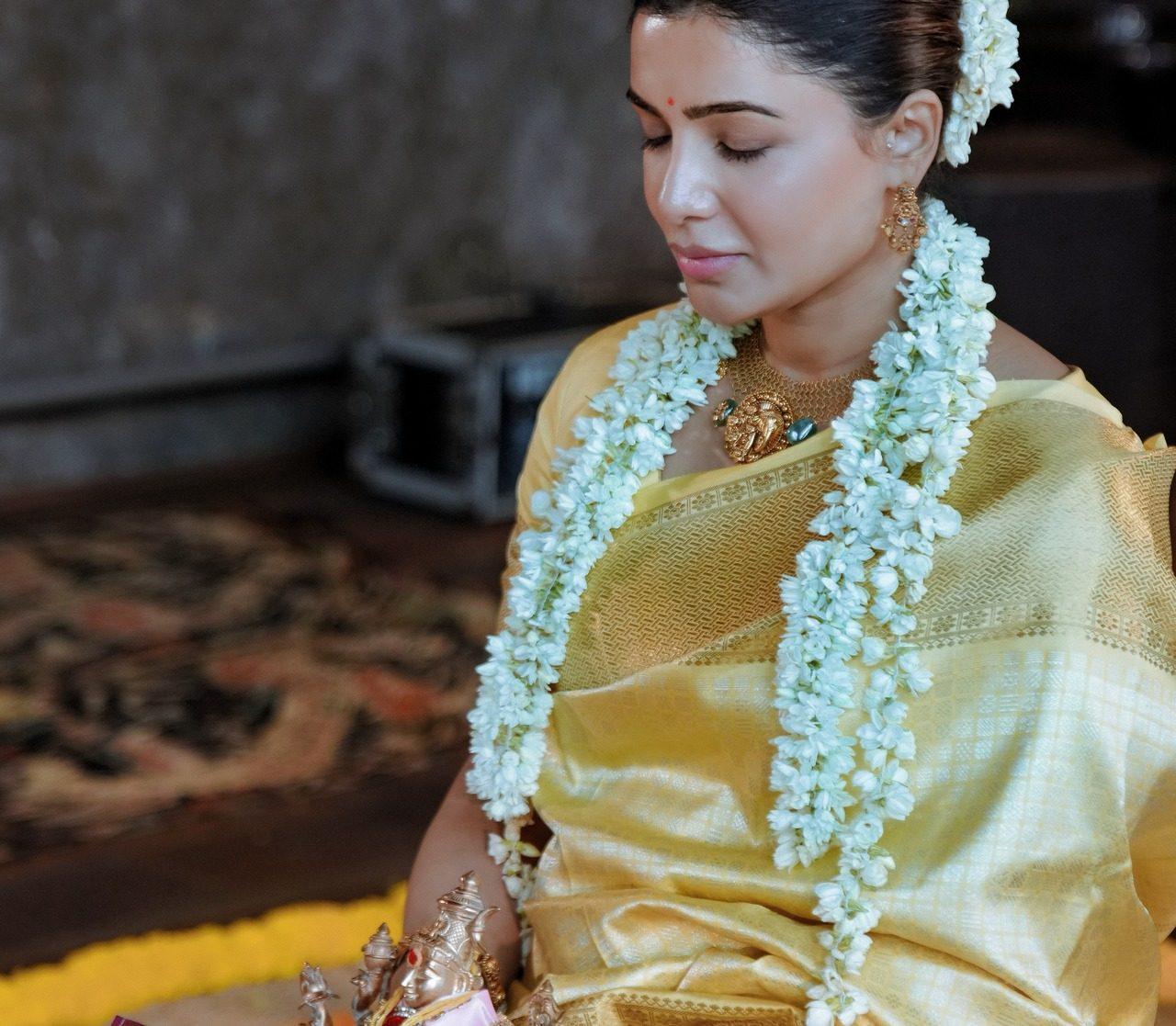 Samantha was seen deeply engrossed in prayer, wearing a classic yellow and gold traditional saree paired with gold temple jewelry. Her hair looked styled in a neat updo with gajra.