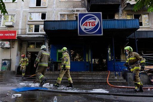 Firefighters work near a damaged supermarket