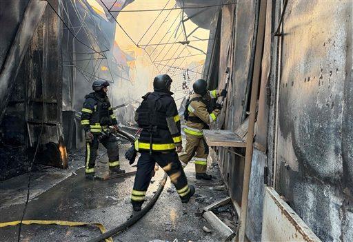 Ukrainian firefighters work to extinguish a fire at a local market following a Russian drone strike in Zaporizhzhia