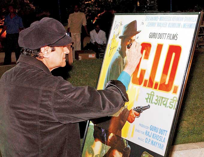 Dev Anand signs a poster of his famous film 'CID'. The poster was auctioned at the launch party of the book Bollywood: Popular Indian Cinema at a Bandra hotel. Picture/mid-day archives