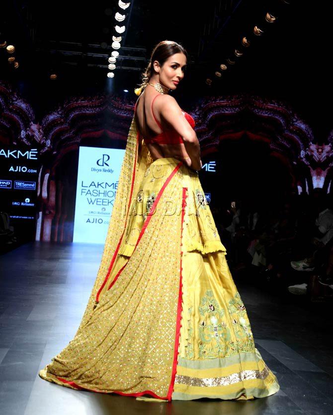 Malaika Arora a simple red choli and intricately embellished yellow layered lehenga, her look was complete with the gold-ish choker, light-red lipstick, and a simple red bindi