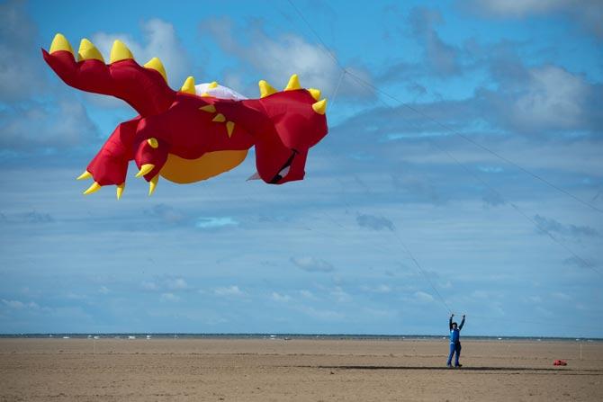 A competitor flies a kite shaped like a large red dragon A competitor flies a kite shaped like a large red dragon