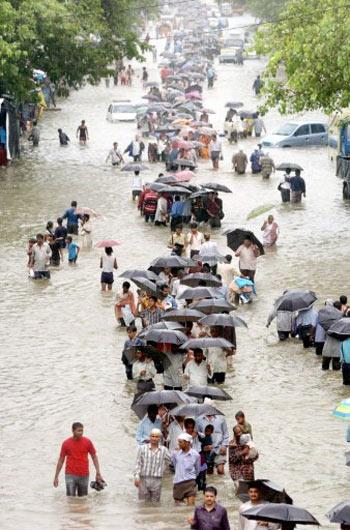 Many people lost their lives and many were also reported missing during the July 26, 2005 floods in Mumbai. In pic: People walk on a flooded street to reach home.
