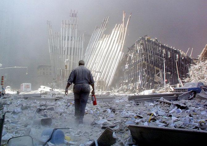 A man with a fire extinguisher walks through rubble after the collapse of the first World Trade Center Tower on September 11, 2001, in New York. The man was shouting as he walked looking for victims who needed assistance. Both towers collapsed after being hit by hijacked passengers planes. Pic/AFP