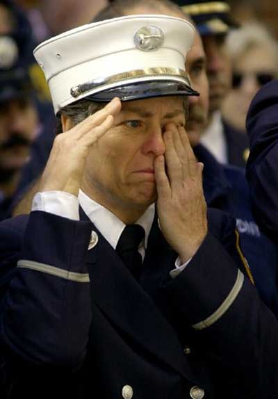 An unidentified firefighter wipes a tear while saluting the casket of New York Fire Department Chaplin Reverend Mychal Judge on September 15, 2001, a victim of the World Trade Center attack in New York. Judge was killed while giving last rites at the scene of the attack. Pic/AFP