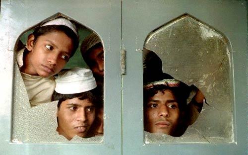 Boys peep through broken glass at a school inside Chunabhatti mosque