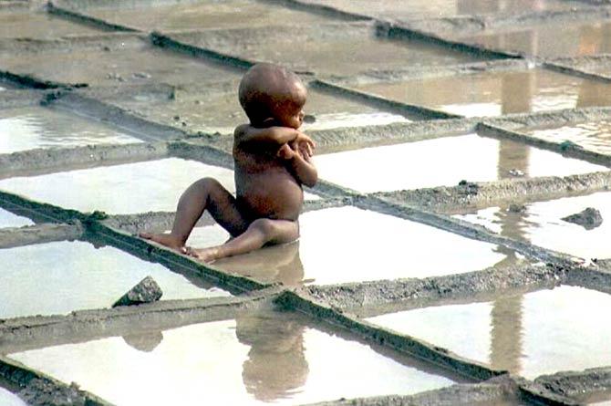A young boy tries to cool himself in a pool of water at a road construction site. All Pics/AFP
