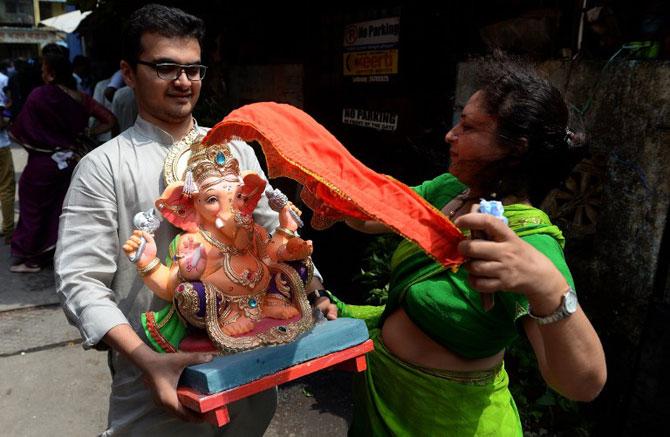 Devotee tries to put back a covering cloth after it was blown away during a sudden gust of wind while transporting an idol of Lord Ganesha from an artist's workshop for Ganesh Chaturthi. Pic/ AFP Devotee tries to put back a covering cloth after it was blown away during a sudden gust of wind while transporting an idol of Lord Ganesha from an artist's workshop for Ganesh Chaturthi. Pic/ AFP