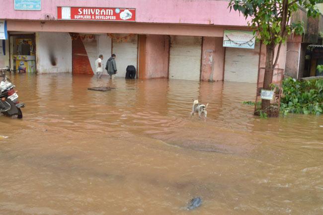 A man stands outside his closed office building and checks for any damages in Hendrepada, Badlapur