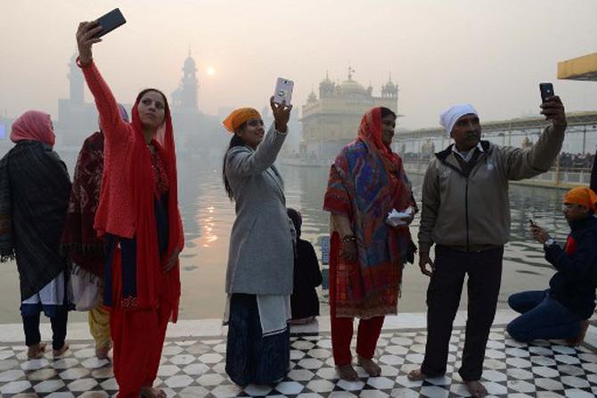 Devotees take selfies as they pay respect on the occasion of New Year at the Golden Temple in Amritsar on January 1, 2018
