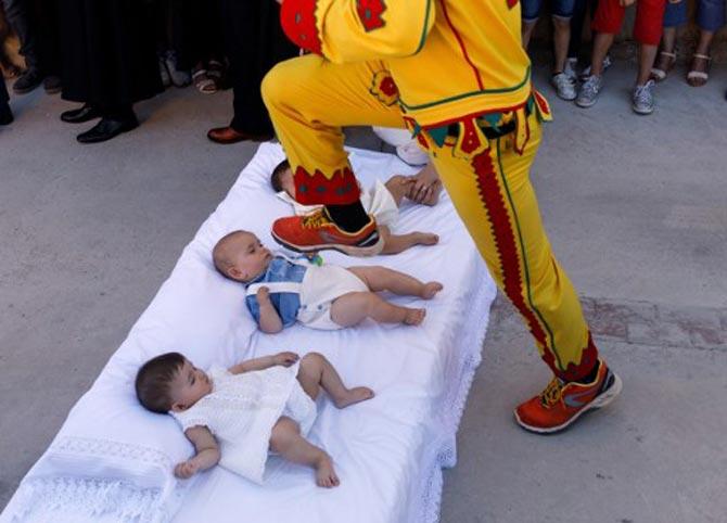 A man dressed up as the devil jumps over babies lying on a mattress in the street during 'El Colacho', the 'baby jumping festival' in the village of Castrillo de Murcia, near Burgos on June 18, 2017. Baby jumping (El Colacho) is a traditional Spanish practice dating back to 1620 that takes place annually to celebrate the Catholic feast of Corpus Christi. During the act - known as El Salto del Colacho (the devil's jump) or simply El Colacho - men dressed as the Devil jump over babies born in the last twelve months of the year who lie on mattresses in the street. Pic/AFP