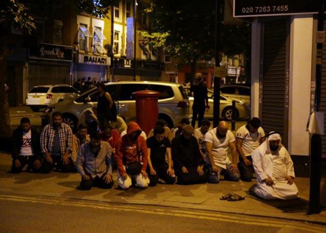 Muslims pray on a sidewalk in the Finsbury Park area of north London after a vehichle hit pedestrians, on June 19, 2017.  One person has been arrested after a vehicle hit pedestrians in north London, injuring several people, police said Monday, as Muslim leaders said worshippers were mown down after leaving a mosque. Pic/AFP