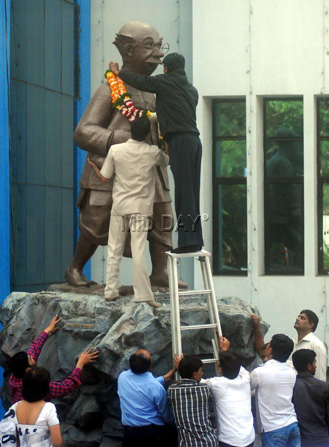 A worker of Symbiosis, Pune garlands the statue of The Common Man