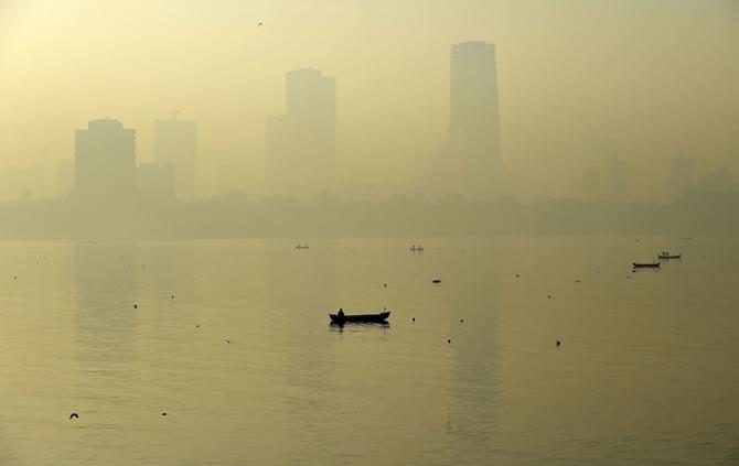 A fishing boat is seen in the morning general view of the city skyline covered by a smoggy haze in Mumbai on January 29, 2016. Pic/AFP