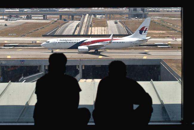 Passengers watch a Malaysia Airlines plane makes its way on the runway at Kuala Lumpur International Airport in Sepang on March 11, 2014