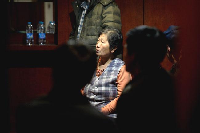 This picture taken on March 10, 2014 shows relatives of passengers on missing Malaysia Airlines flight MH370 watching television news for the latest updates in a waiting lounge at the Lido Hotel in Beijing 