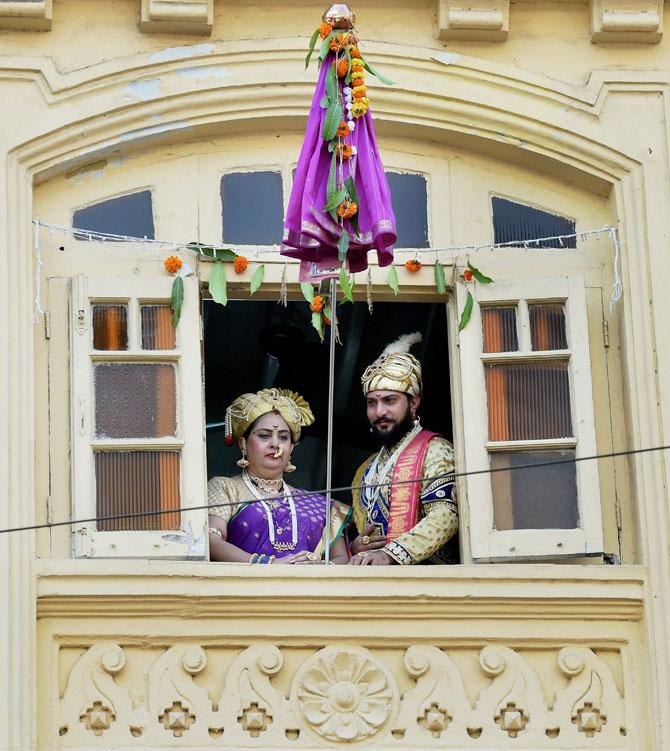 A man and woman dressed up in traditional attire watch as people throng the streets in Mumbai to celebrate the Maharashtrian new year 'Gudi Padwa' in Thane