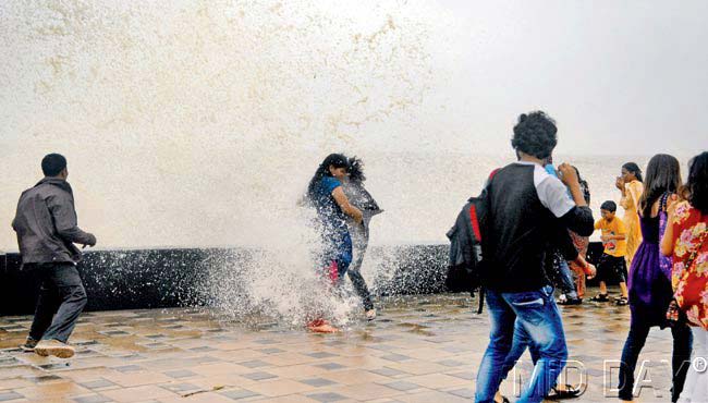 Two women get splashed by the turbulent sea on Marine drive. The image is extremely impactful since it perfectly captures the monsoons of Mumbai