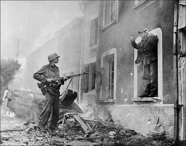 An American soldier points his rifle at a German soldier surrendering during the battle for France's liberation, western France, in 1944