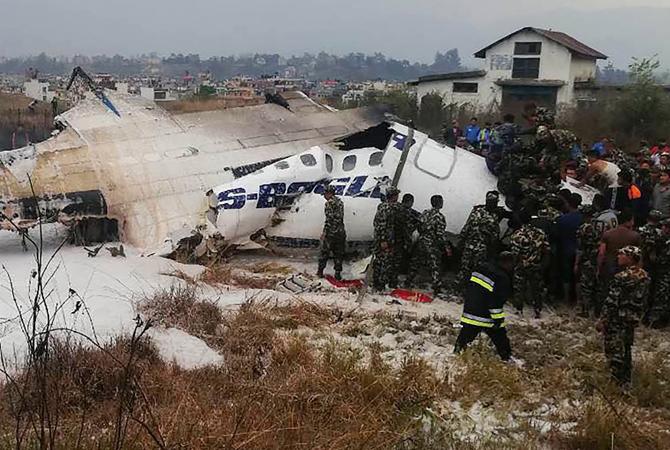 This picture obtained from the Twitter account of Saroj Basnet shows Nepali rescue workers gathered around the debris of that airplane that crashed near the international airport in Kathmandu. Pic courtesy/ Twitter account of Saroj Basnet (@IsarojB)