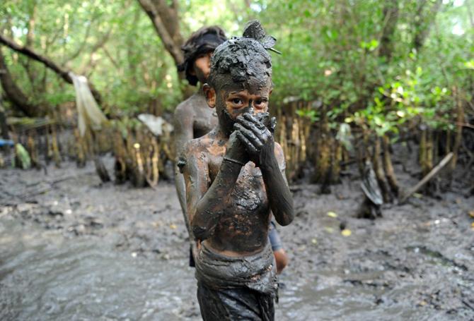 A boy poses for the camera during Mebuug-buugan in Bali's Kedonganan village