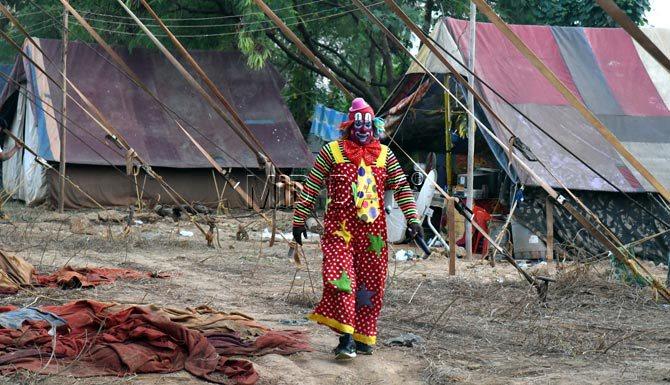 A man dressed as a clown looks like he's out for a stroll during one of his breaks at Rambo Circus